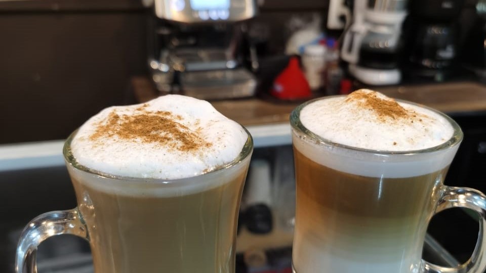 Dos capuchinos servidos en tazas de cristal.